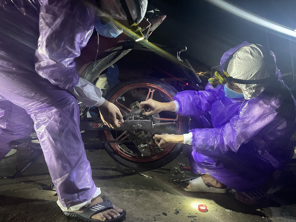  Sinh viên tình nguyện trong đội SOS của trường Đại học Đông Á Đà Nẵng sửa chữa xe miễn phí cho người dân các tỉnh, thành trên đường trở về nhà khi đi qua thành phố Đà Nẵng. (Ảnh: TTXVN phát)