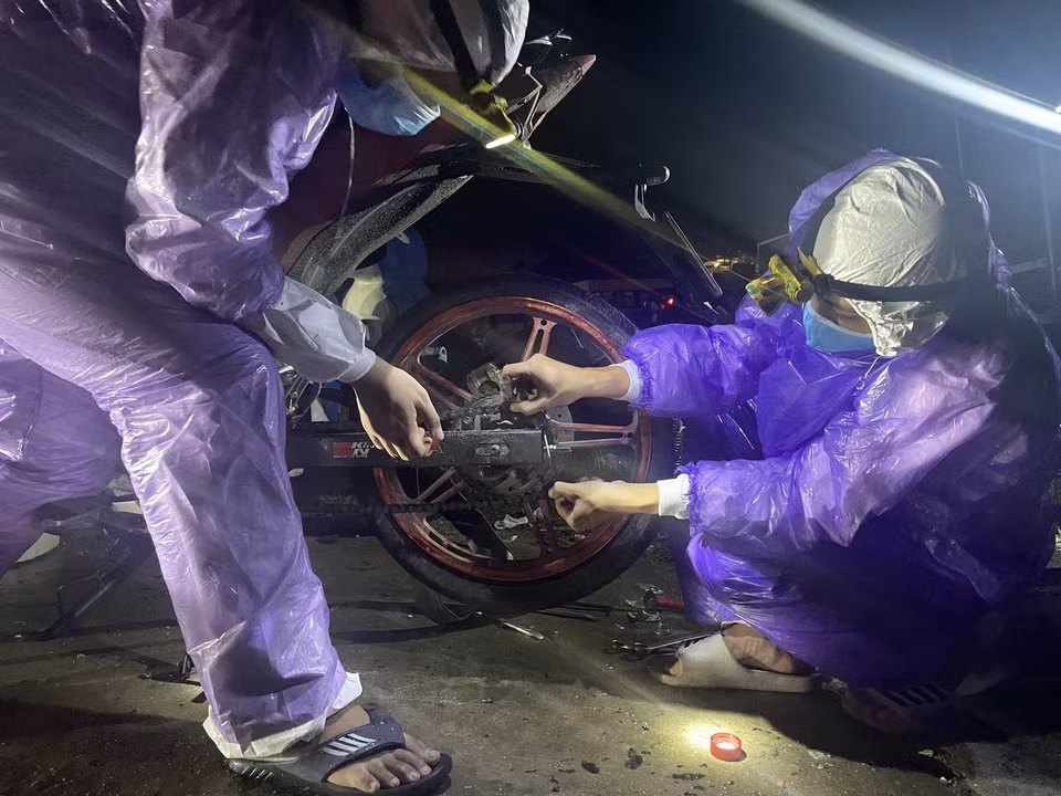  Sinh viên tình nguyện trong đội SOS của trường Đại học Đông Á Đà Nẵng sửa chữa xe miễn phí cho người dân các tỉnh, thành trên đường trở về nhà khi đi qua thành phố Đà Nẵng. (Ảnh: TTXVN phát)