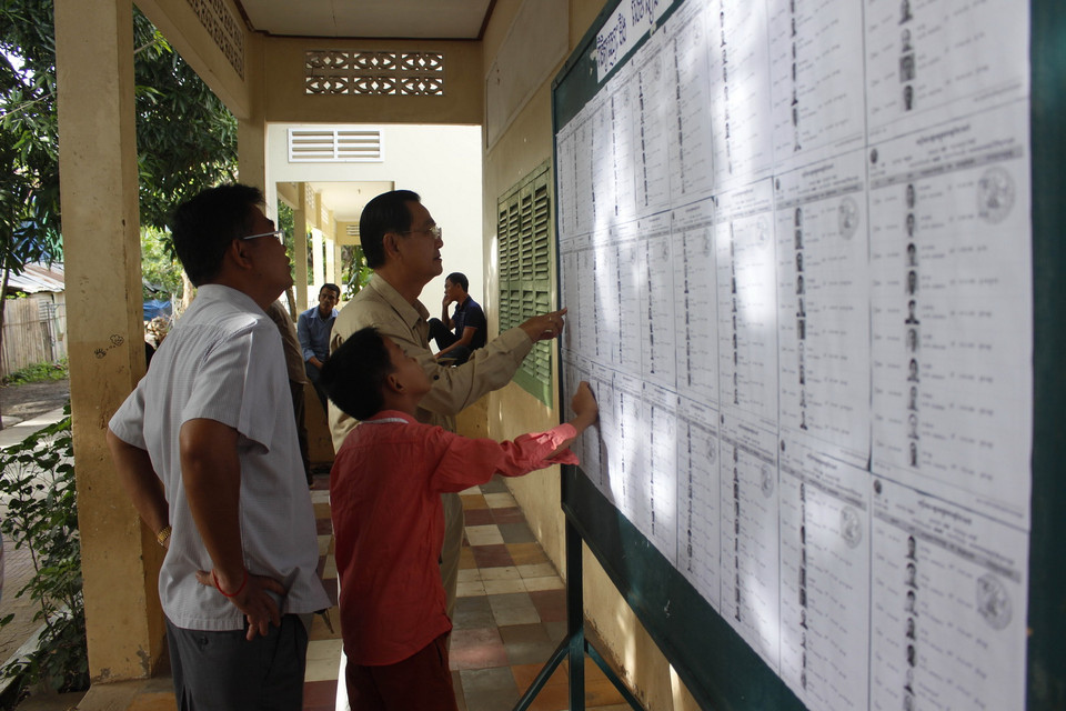Cử tri kiểm tra tên của mình trong danh sách cử tri trước phòng phiếu 1697 ở thành phố Ta Khmau, tỉnh Kandal. 
