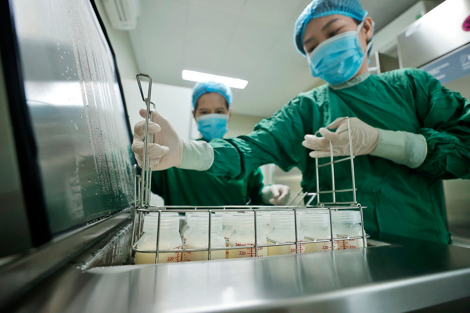 Nhân viên y tế cho sữa vào thanh trùng trước khi được chuyển tới các khoa cho bệnh nhi. (Ảnh: Minh Quyết/TTXVN)