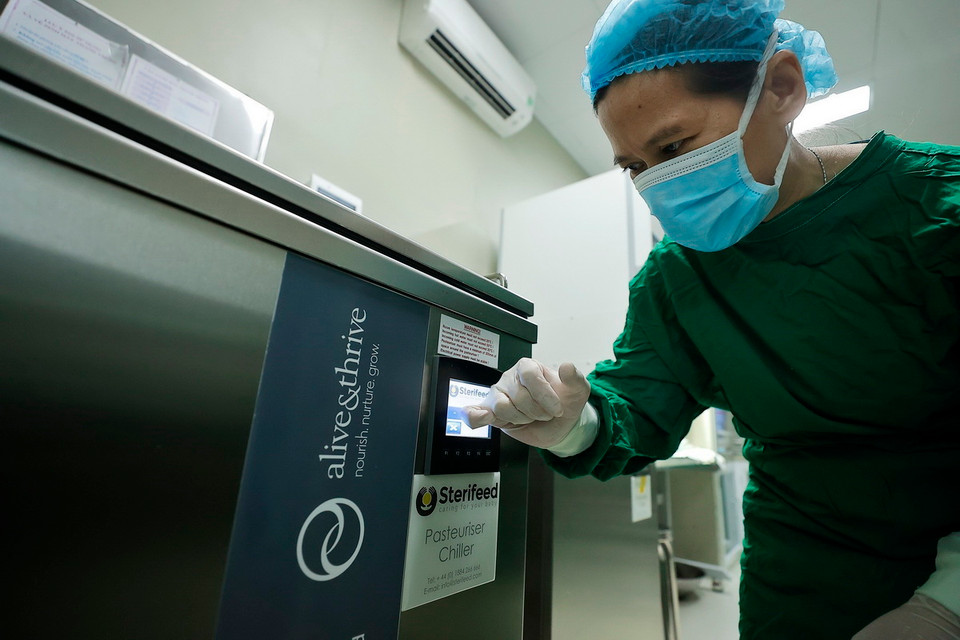 Nhân viên y tế cho sữa vào thanh trùng trước khi được chuyển tới các khoa cho bệnh nhi. (Ảnh: Minh Quyết/TTXVN)