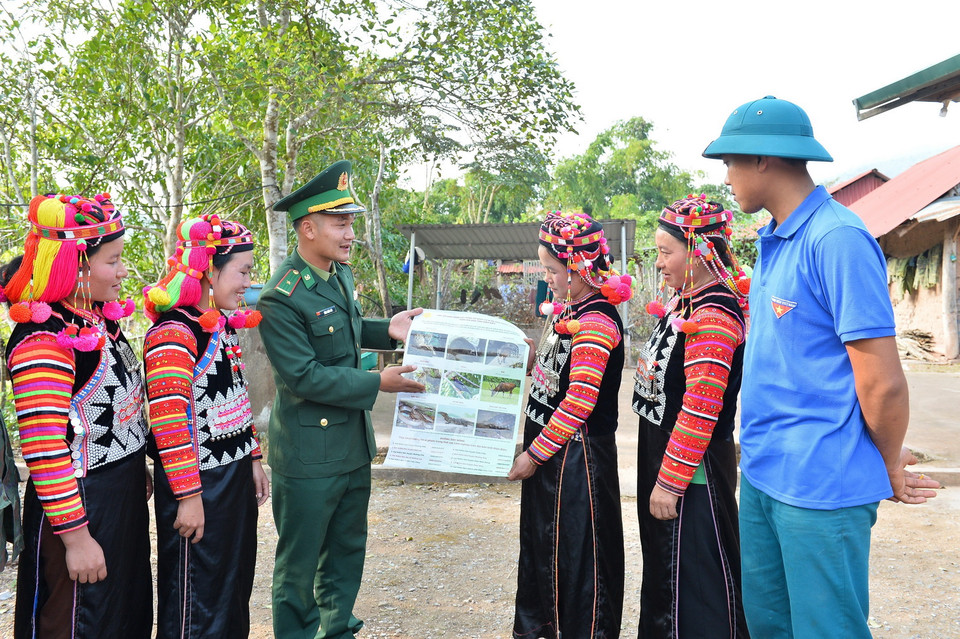 Cán bộ Đồn Biên phòng A Pa Chải tuyên truyền công tác bảo vệ tài nguyên, không săn bắt thú rừng với bà con dân tộc người Hà Nhì. (Ảnh: Minh Đức/TTXVN)