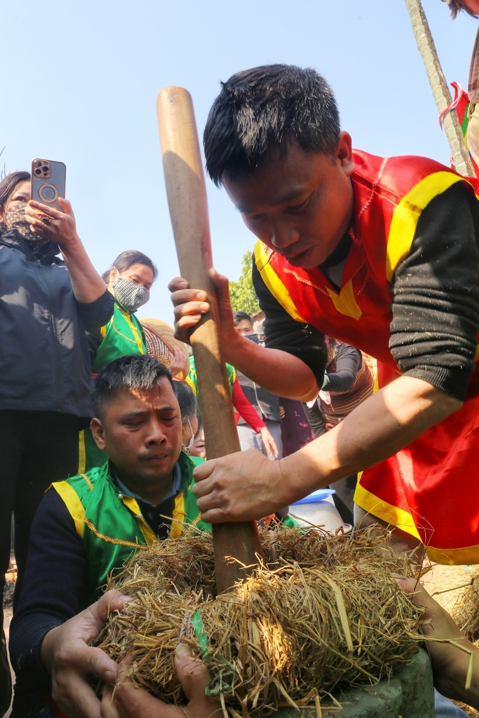 Các nam thanh niên biểu diễn kỹ thuật giã thóc lấy gạo. (Ảnh: Tuấn Đức/TTXVN)