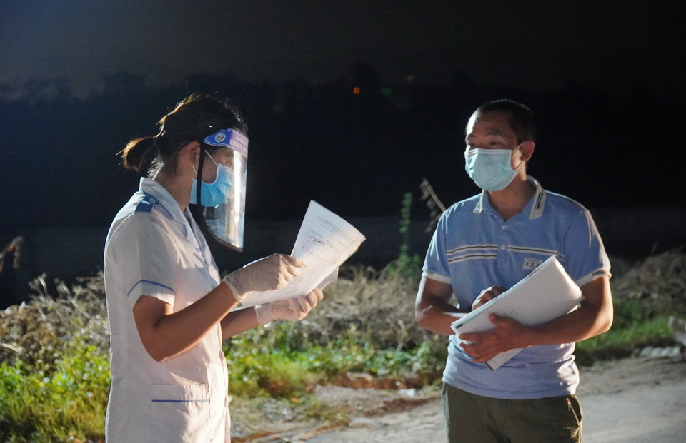 Lực lượng y tế tại chốt kiểm dịch chân cầu Yên Dũng nối tỉnh Bắc Ninh và Bắc Giang hỗ trợ người dân khai báo y tế. (Ảnh: Đinh Văn Nhiều/TTXVN)