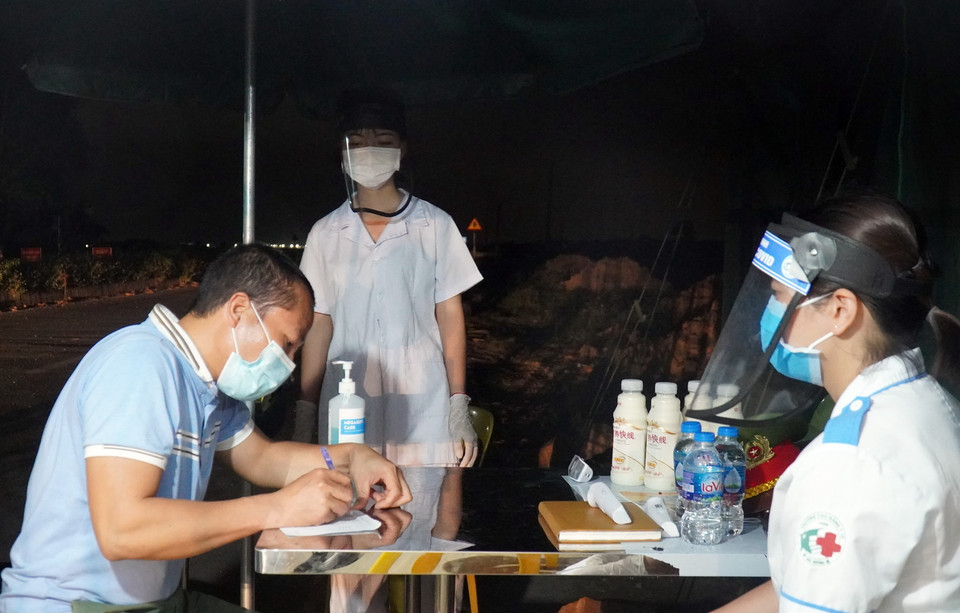 Lực lượng y tế tại chốt kiểm dịch chân cầu Yên Dũng nối tỉnh Bắc Ninh và Bắc Giang hỗ trợ người dân khai báo y tế. (Ảnh: Đinh Văn Nhiều/TTXVN)