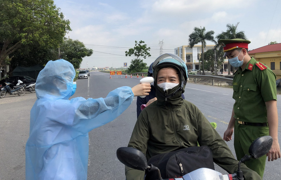 Các lực lượng tại chốt kiểm dịch xã Nghĩa Đạo, huyện Thuận Thành đo thân nhiệt cho người dân. (Ảnh: Đinh Văn Nhiều/TTXVN)