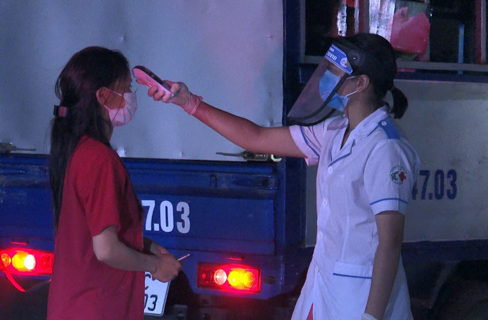 Lực lượng y tế tại chốt kiểm dịch chân cầu Yên Dũng nối tỉnh Bắc Ninh và Bắc Giang đo thân nhiệt cho người dân. (Ảnh: Đinh Văn Nhiều/TTXVN)