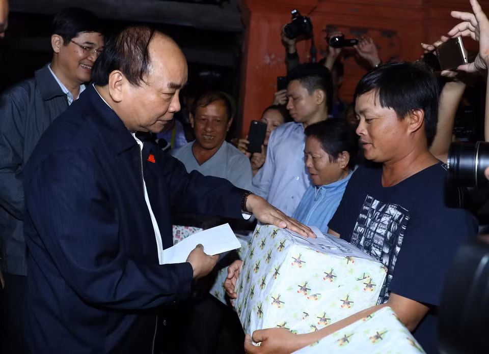 Thủ tướng Nguyễn Xuân Phúc tặng quà cho các gia đình bị ngập lụt do mưa lũ. (Ảnh: Thống Nhất/TTXVN)
