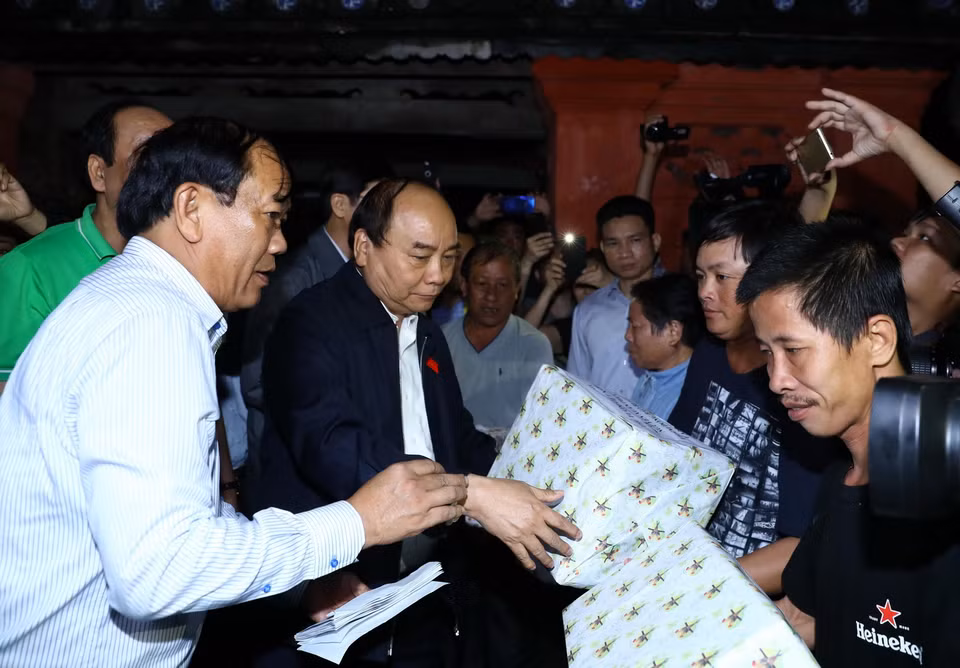 Thủ tướng Nguyễn Xuân Phúc tặng quà cho các gia đình bị ngập lụt do mưa lũ. (Ảnh: Thống Nhất/TTXVN)