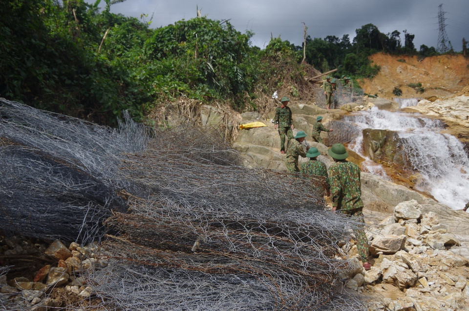 Lực lượng quân đội vận chuyển rọ đá để tổ chức nắn dòng suối Rào Trăng. (Ảnh: TTXVN phát)