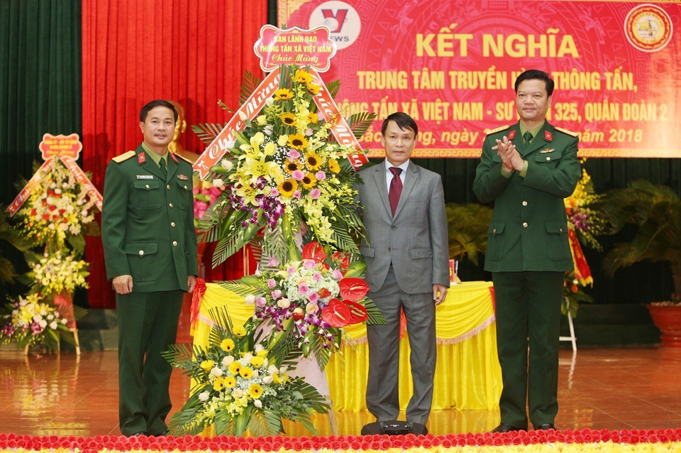 Tổng Giám đốc TTXVN Nguyễn Đức Lợi tặng hoa, chúc mừng Sư đoàn 325. (Ảnh: Dương Giang/TTXVN)