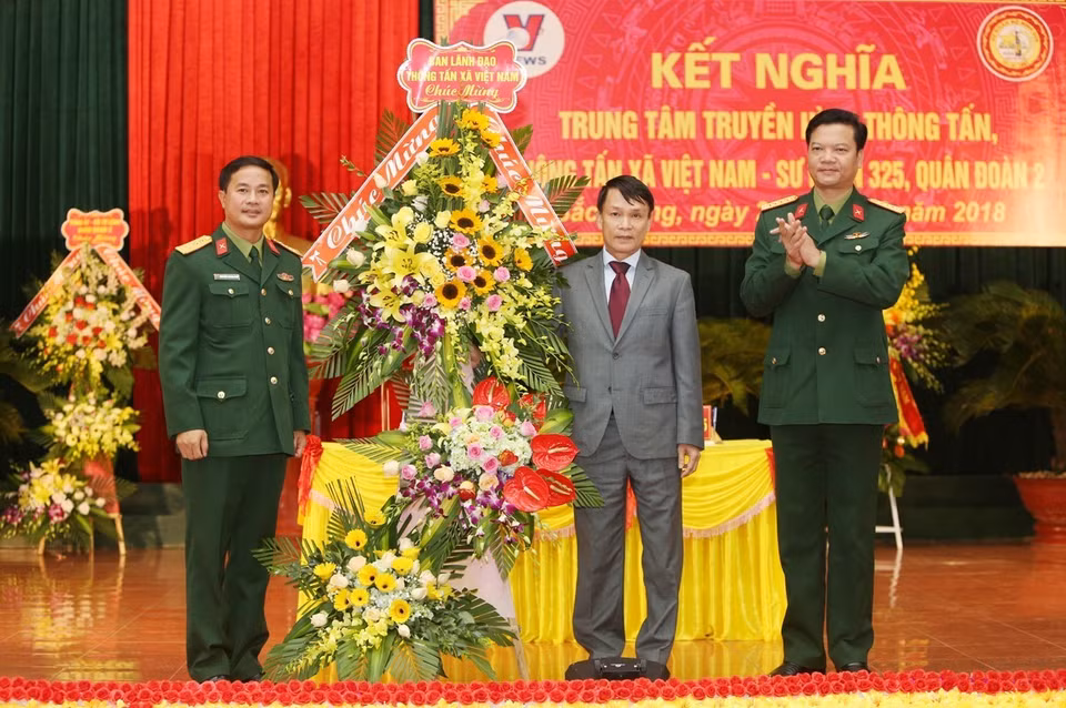 Tổng Giám đốc TTXVN Nguyễn Đức Lợi tặng hoa, chúc mừng Sư đoàn 325. (Ảnh: Dương Giang/TTXVN) 