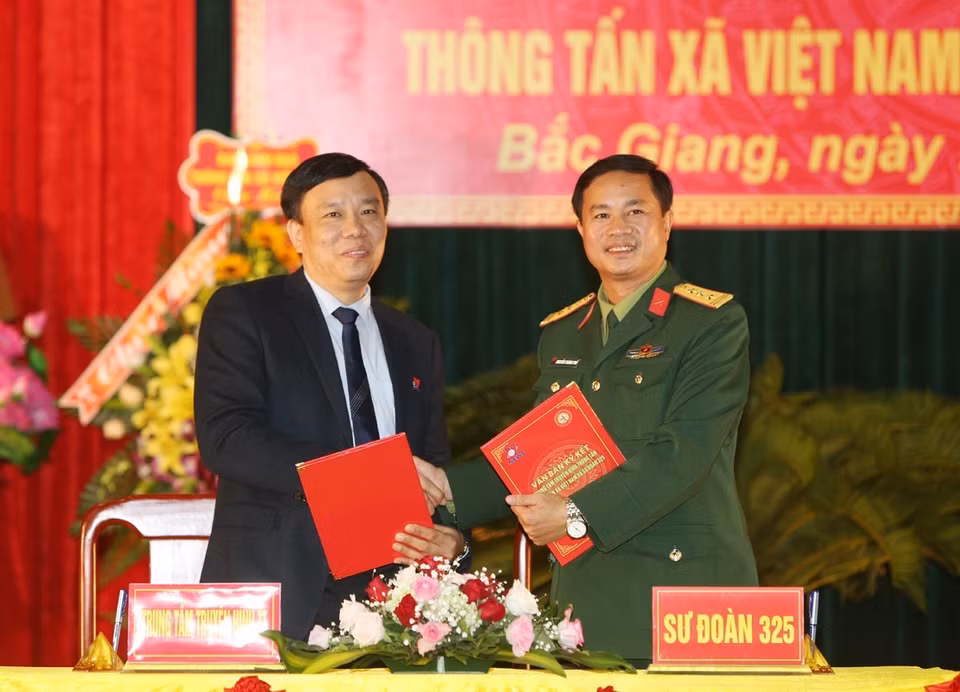 Giám đốc Truyền hình Thông tấn Nguyễn Thiện Thuật và Thượng tá Nguyễn Thành Phố, Sư đoàn trưởng Sư đoàn 325 ký biên bản kết nghĩa. (Ảnh: Dương Giang/TTXVN)