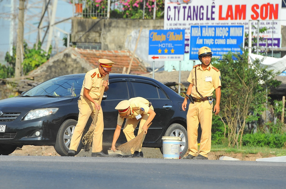 Các chiến sỹ Cảnh sát giao thông thành phố Ninh Bình dọn đất đá rơi vãi để đảm bảo an toàn giao thông. (Ảnh: Minh Đức/TTXVN)