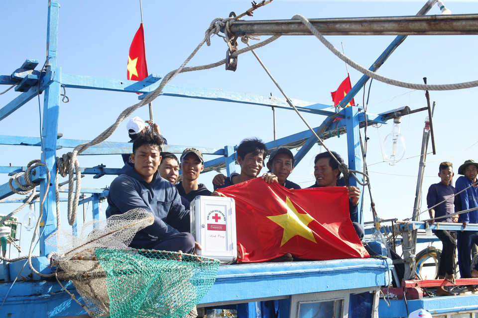 Ngư dân tại cảng cá phấn khởi khi có Quốc kỳ mới. (Ảnh: Tùng Lâm/Vietnam+)