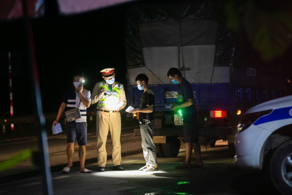  Lực lượng chức năng thực hiện kiểm soát người và phương tiện trong đêm lưu thông qua chốt. (Ảnh: Trọng Đạt/TTXVN)