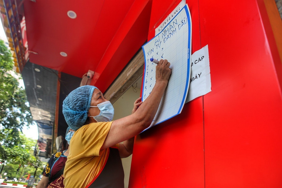 Sau khi nhận cơm, người nhận được đánh dấu lên bảng để tránh nhầm lẫn. (Ảnh: Tuấn Đức/TTXVN)