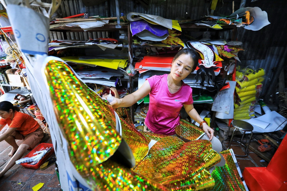 Chăm chút dán và ghép sản phẩm vàng mã. (Ảnh: Thành Đạt/TTXVN)