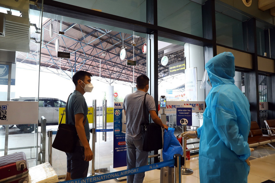Hành khách tới sân bay Nội Bài phải đo kiểm tra thân nhiệt. (Ảnh: Huy Hùng/TTXVN)
