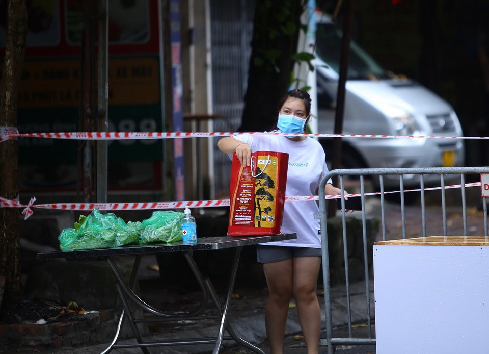  Người dân trong khu vực phong tỏa nhận hàng tại rào chắn phong tỏa ngõ 24 Kim Đồng. (Ảnh: Hoàng Hiếu/TTXVN) 