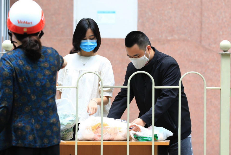 Người dân sinh sống tại tòa chung cư nhận đồ tiếp tế của người thân tại chốt kiểm tra. (Ảnh: Thành Đạt/TTXVN)