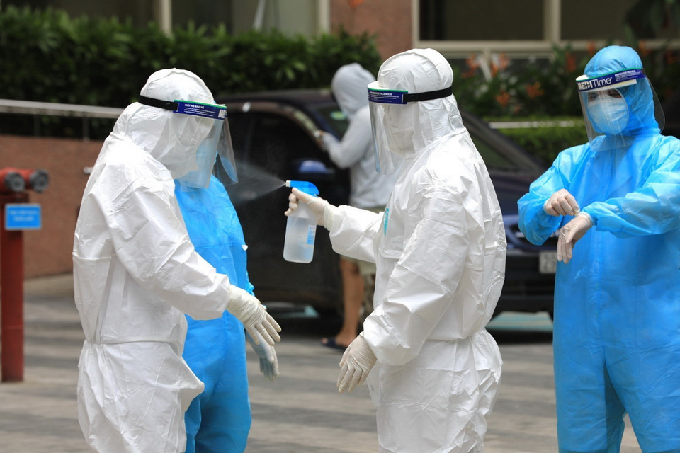  Nhân viên y tế quận Hà Đông tiến hành phun khử khuẩn toàn bộ thân thể quần áo sau khi làm nhiệm vụ xong. (Ảnh: Thành Đạt/TTXVN)