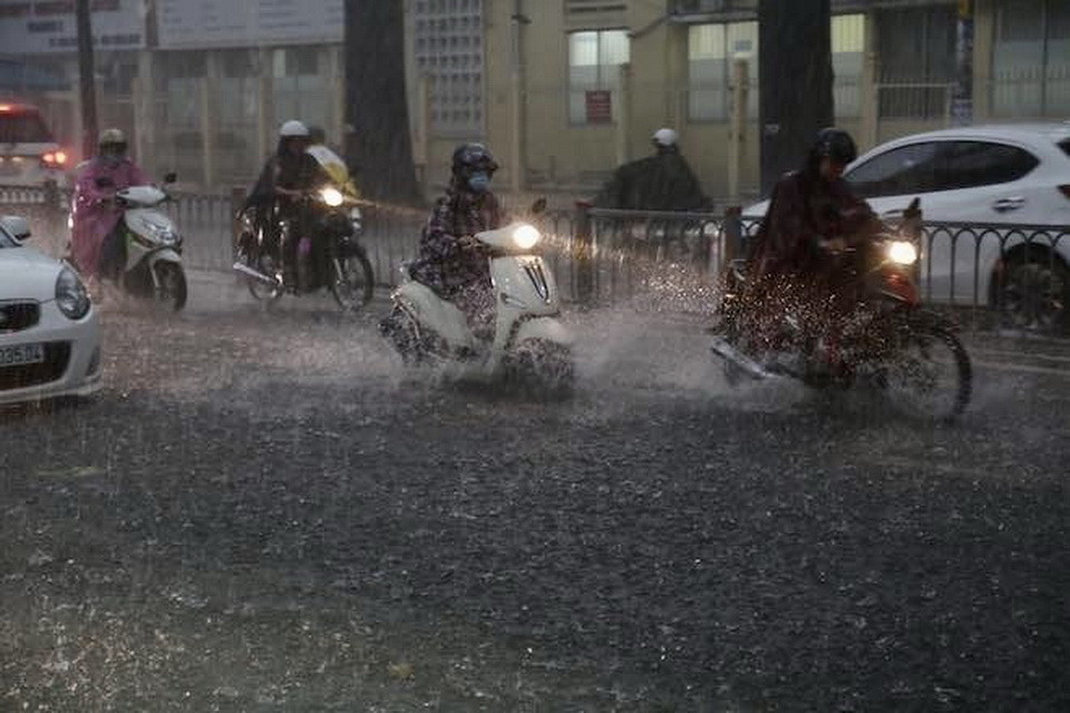 Người dân điều khiển phương tiện trong cơn mưa mịt mù trên đường Hồ Học Lãm, quận Bình Tân. (Ảnh: Hồng Giang/TTXVN)