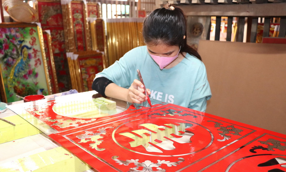 Trước đây, các nghệ nhân sẽ vẽ tay 100% các hoa văn, chữ viết, đường viền... Trong ảnh: Nghệ nhân trang trí, sơn mặt sau tranh kính. (Ảnh: Thanh Sang/TTXVN)