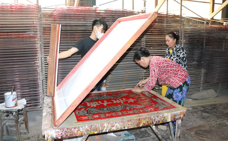 Hiện nay, các hộ đã đầu tư máy móc, ứng dụng công nghệ để làm tranh. Trong ảnh: Tranh kính được sử dụng phương pháp kéo lụa sản xuất đại trà nên giá thành tương đối rẻ. (Ảnh: Thanh Sang/TTXVN)