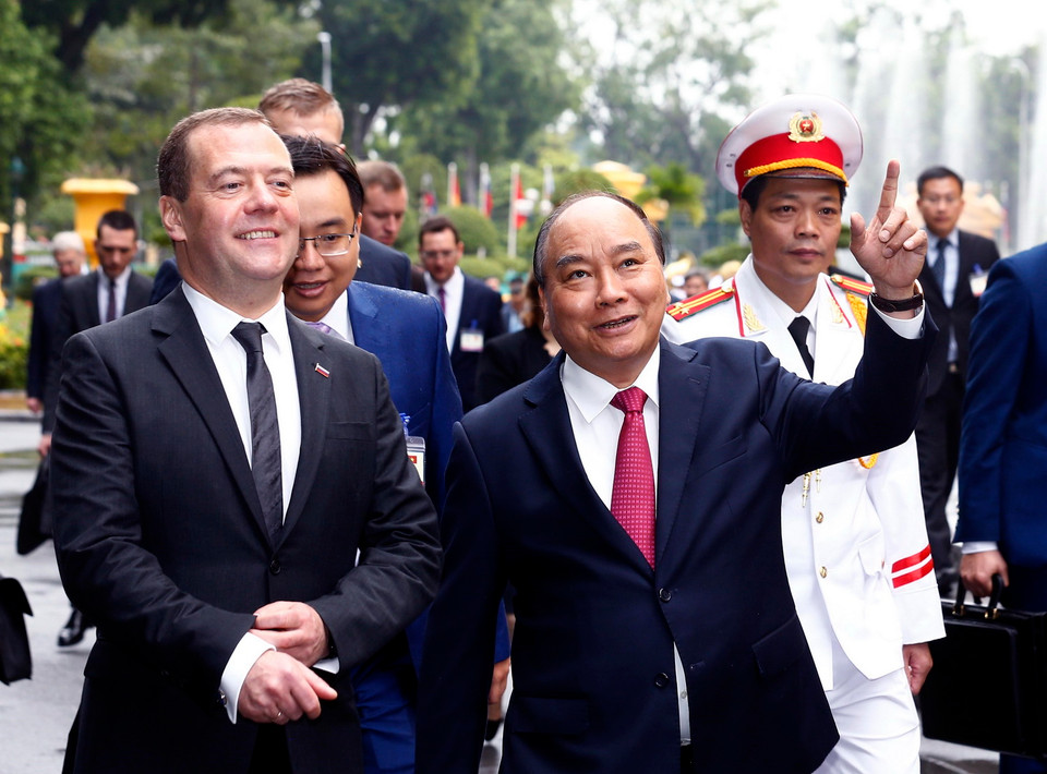 Thủ tướng Nguyễn Xuân Phúc giới thiệu với Thủ tướng Nga Dmitry Anatolyevich Medvedev về cảnh quan Khu di tích Phủ Chủ tịch trên đường tới Văn phòng Chính phủ. (Ảnh: Thống Nhất/TTXVN)