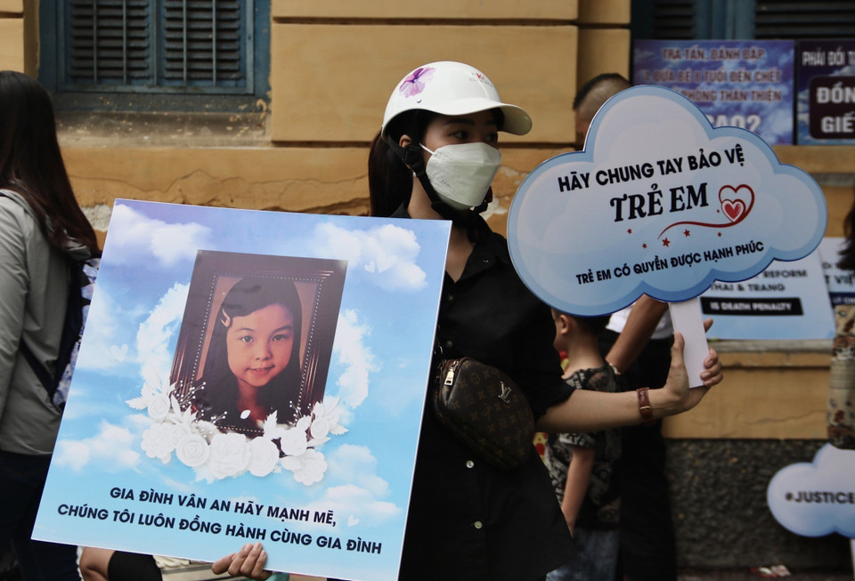 Người dân cầm biểu ngữ ủng hộ người bị hại. (Ảnh: Thanh Vũ/TTXVN)