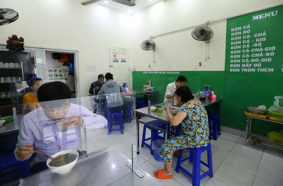 Quán bún cá trên phố Mai Hắc Đế lắp tấm chắn đảm bảo an toàn phòng, chống COVID-19. (Ảnh: Hoàng Hiếu/TTXVN)