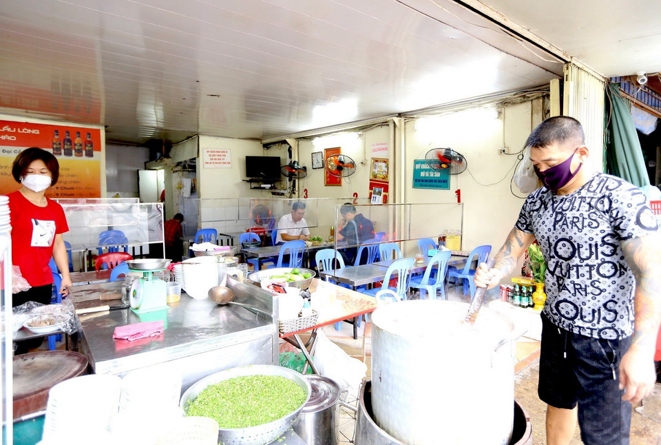Một quán ăn phố Đại Cồ Việt mở cửa, lắp tấm chắn đảm bảo an toàn phòng dịch. (Ảnh: Hoàng Hiếu/TTXVN)