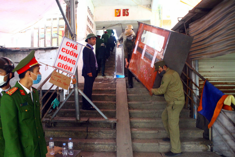 Lực lượng chức năng vận chuyển đồ đạc của người dân ra khỏi chung cư Quang Trung. (Ảnh: Tá Chuyên/TTXVN)