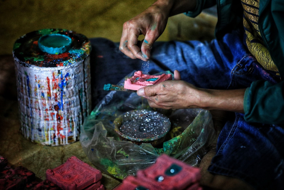 Sau khi nung, những bức tượng ông Táo được người dân vẽ bằng màu rồi rắc bột kim tuyến để trông bắt mắt hơn. (Ảnh: Thành Đạt/TTXVN)