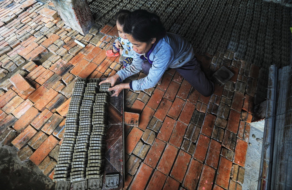 Để tượng không bị vỡ nát, hư hỏng, khi đưa tượng vào lò, người thợ cần phải sắp xếp thành từng hàng, nhiều lớp trên dưới xen kẽ, giữa các lối cần có khoảng cách để lửa cháy đều. (Ảnh: Thành Đạt/TTXVN)