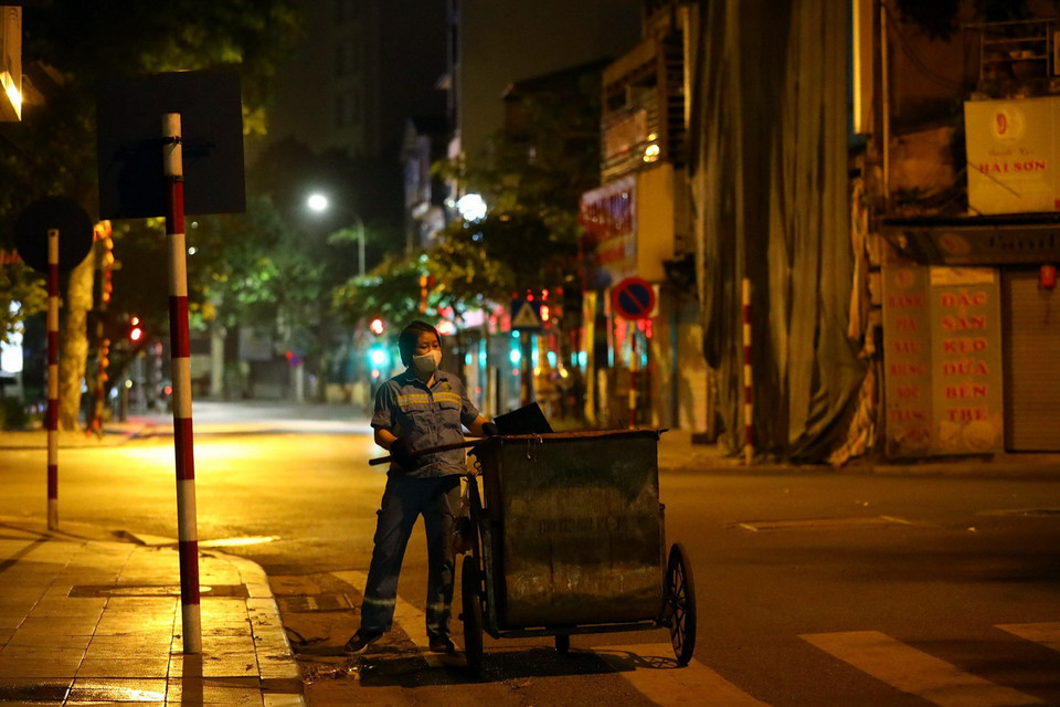 Một chị lao công đang dọn vệ sinh tại góc phố Thợ Nhuộm-Hai Bà Trưng. (Ảnh: Huy Hùng/TTXVN)