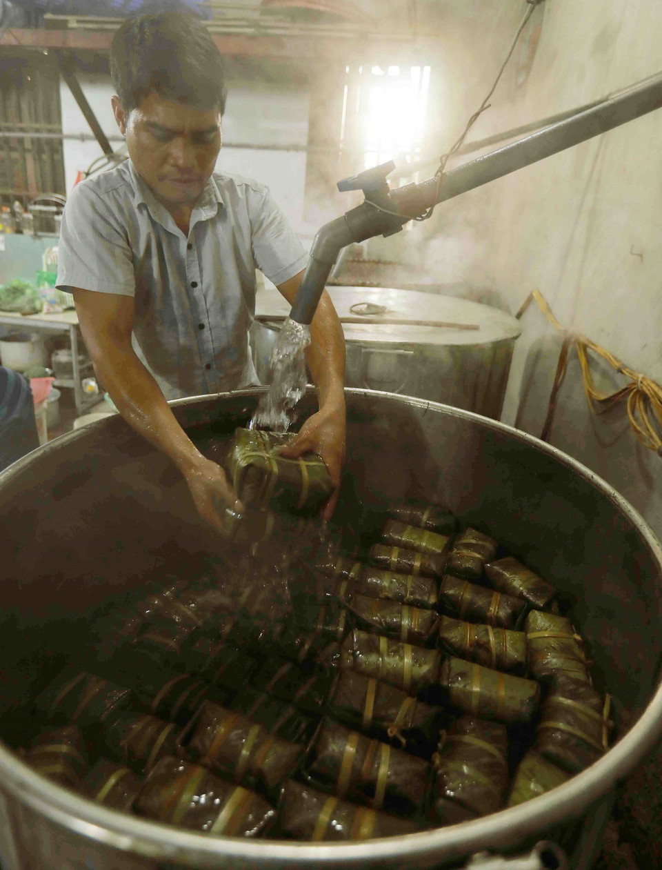 Bánh chưng được luộc trong khoảng 9 tiếng. Sau khi vớt, người ta rửa bánh qua nước lạnh cho bánh sạch và lá không bị khô. (Ảnh: Vũ Sinh/TTXVN)