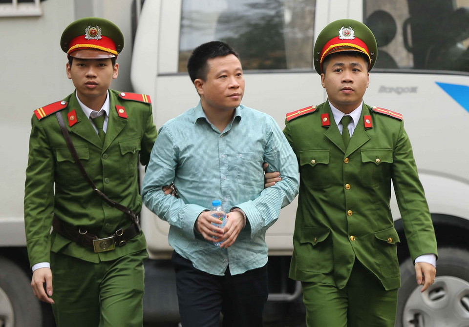 Cảnh sát dẫn giải bị cáo Hà Văn Thắm (nguyên Chủ tịch Hội đồng quản trị OceanBank) vào phòng xét xử. (Ảnh: Doãn Tấn/TTXVN)