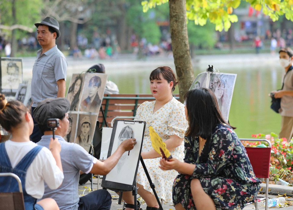 Du khách làm mẫu để có bức ký họa làm kỷ niệm cho mình khi đến với Hồ Gươm. (Ảnh: Thanh Tùng/TTXVN)