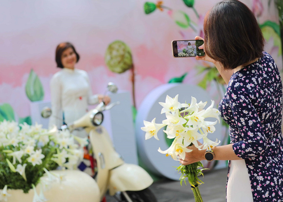 Ngày nghỉ lễ cũng là dịp để chị em phụ nữ xúng xính áo dài cùng lưu lại những khoảnh khắc đẹp của Hà Nội trong mùa hoa loa kèn. (Ảnh: Thanh Tùng/TTXVN)