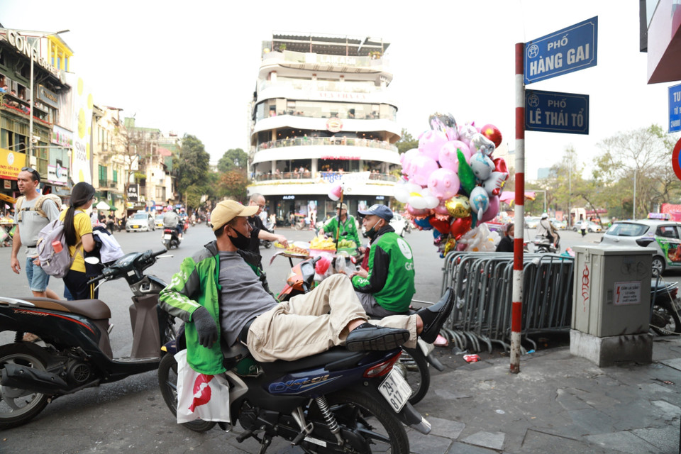 Lòng đường, vỉa hè hiện như một địa điểm để ‘nghỉ ngơi’ của nhiều tài xế công nghệ. (Ảnh: Thanh Thảo/TTXVN phát)