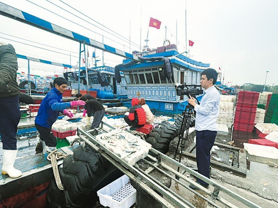 Phóng viên Nguyễn Đình Nam, Cơ quan thường trú Thông tấn xã Việt Nam tại Thanh Hóa ghi hình cảng cá Lạch Bạng, Nghi Sơn, tháng 1/2023. (Ảnh: TTXVN)