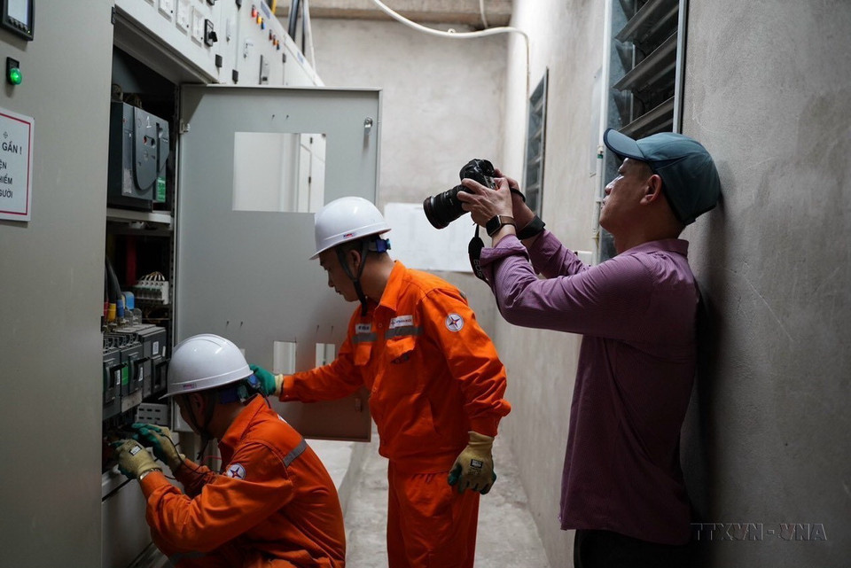 Phóng viên Huy Hùng (Ban Biên tập Ảnh) tác nghiệp tại trạm biến áp của 1 khu chung cư tại quận Hoàng Mai (Hà Nội) trong đợt thiếu điện 6/2023. (Ảnh: TTXVN)