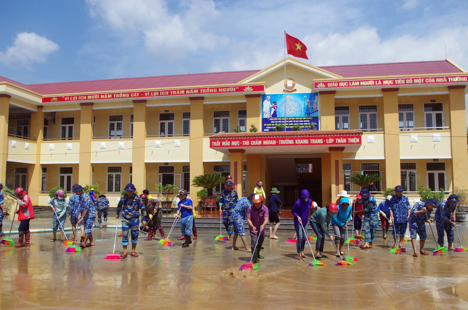  Cán bộ, chiến sỹ Hải đội 102 thuộc Bộ Tư lệnh Vùng Cảnh sát biển 1, cùng các thầy, cô giáo trường Tiểu học Cồn Sẻ làm vệ sinh phòng học, sân trường do mưa lũ gây ra. (Ảnh: TTXVN)