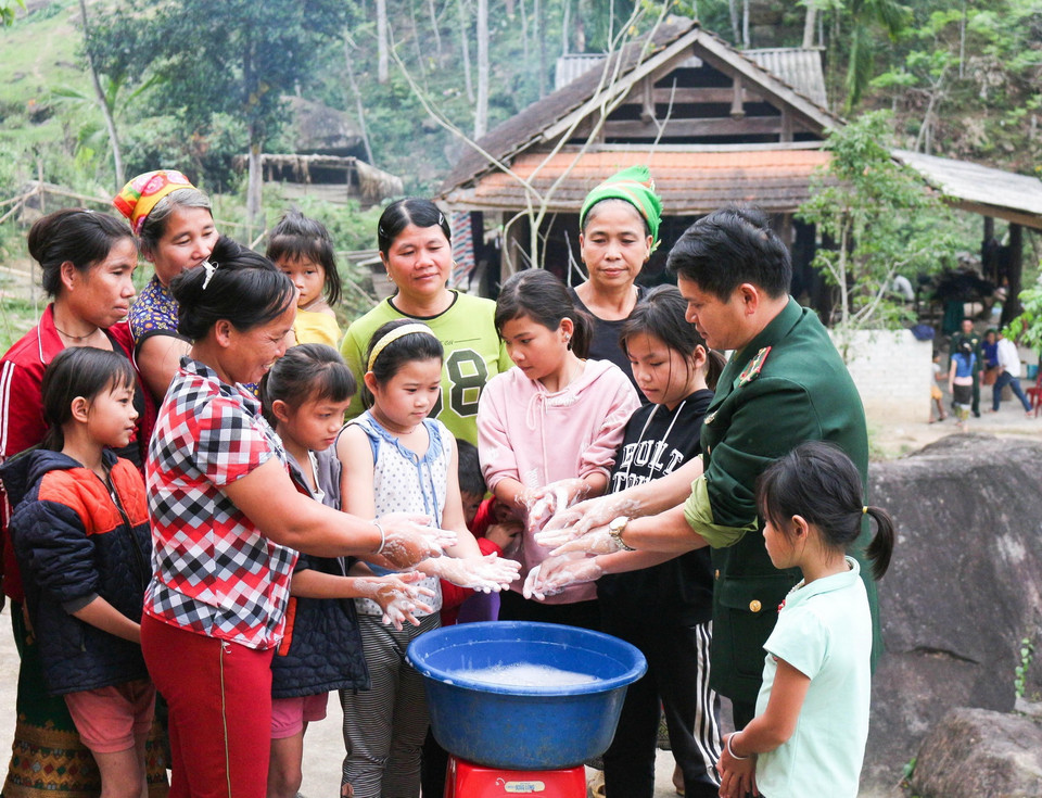  Bộ đội biên phòng đồn Hạnh Dịch, huyện Quế Phong, tỉnh Nghệ An, hướng dẫn bà con cách rửa tay phòng chống dịch COVID 19. (Ảnh: Nguyễn Oanh/TTXVN)