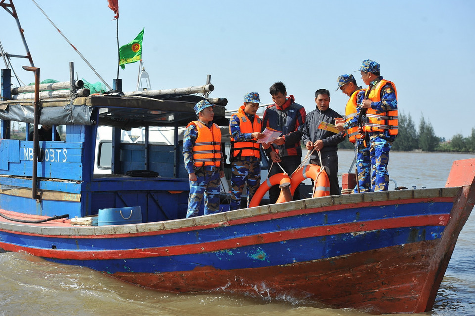  Cán bộ chiến sỹ Hải đội 2 (Ninh Bình) tuyên truyền, phổ biến, giáo dục pháp luật cho nhân dân và phát áo phao cho ngư dân ở khu vực biên giới biển. (Ảnh: Minh Đức/TTXVN)