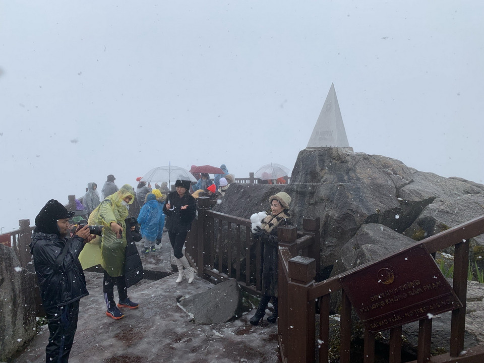  Khách du lịch thích thú với hiện tượng tuyết rơi trên đỉnh Fansipan. (Ảnh: Quốc Khánh/TTXVN)