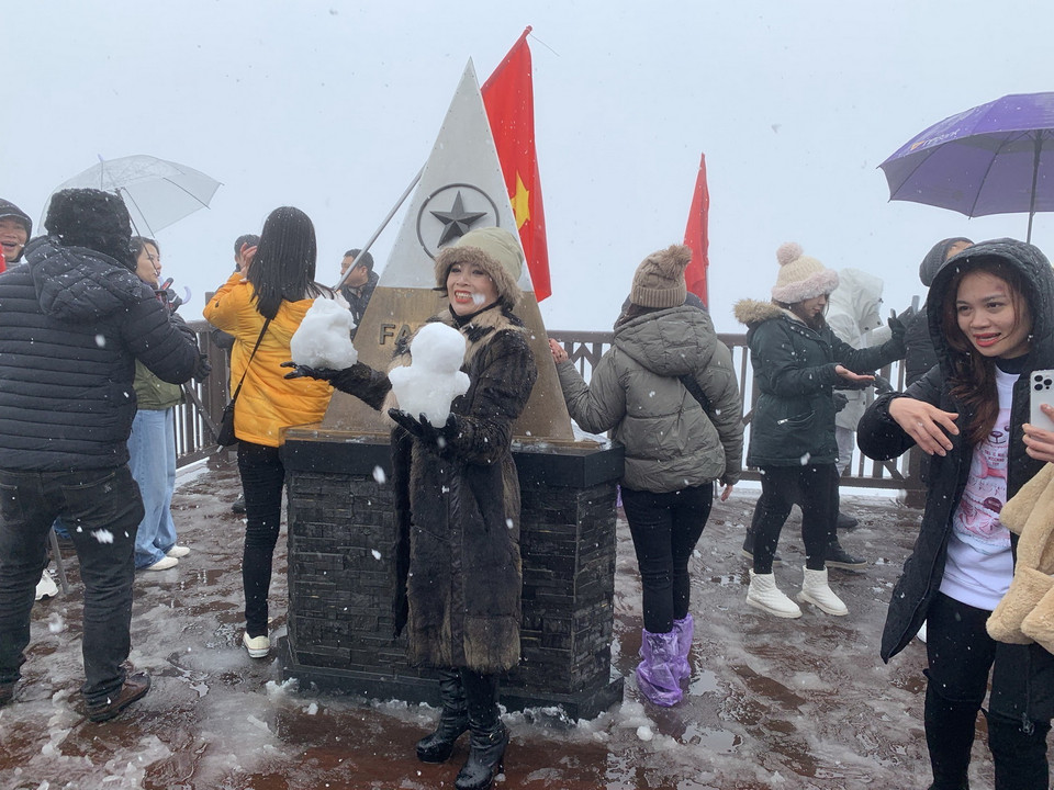  Khách du lịch thích thú chụp ảnh với bông tuyết trên đỉnh Fansipan. (Ảnh: Quốc Khánh/TTXVN)