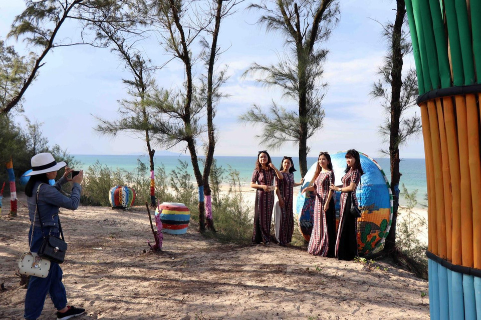 Khách du lịch chụp ảnh bên các tác phẩm hội họa. (Ảnh: Đỗ Trưởng/TTXVN)